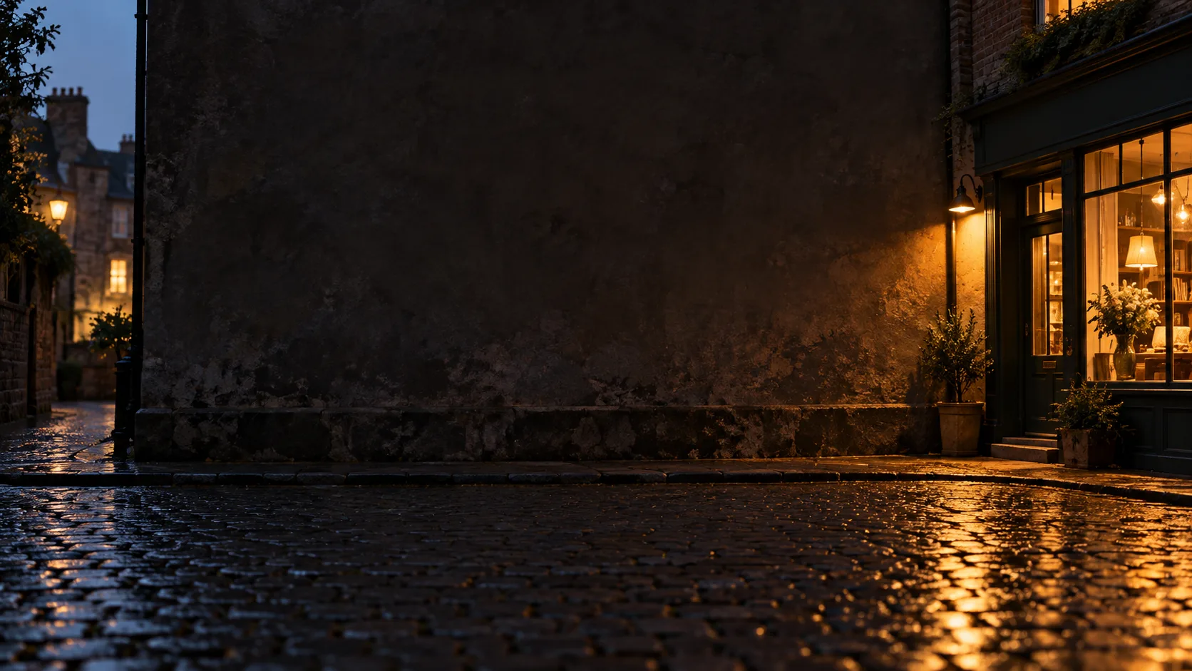 A small shopfront glowing warmly at dusk on a wet cobbled street, a stone wall filling the rest of the frame.