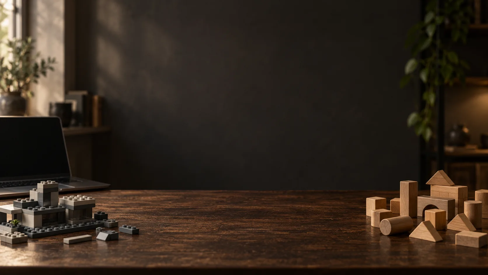 A neat plastic building-block model on one side of a desk and loose wooden blocks on the other.